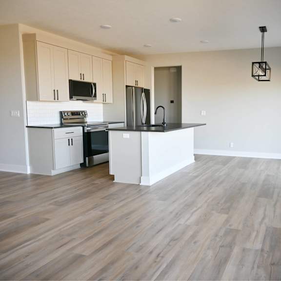a kitchen with a white countertop and wooden flooring.