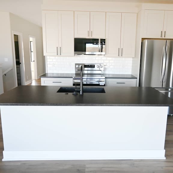 a kitchen with a black countertop and stainless steel appliances.