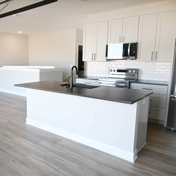 a modern kitchen with a large island and a ceiling fan.