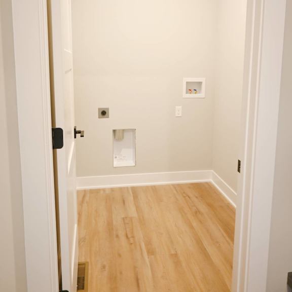 a white door is open to a room with wood flooring.