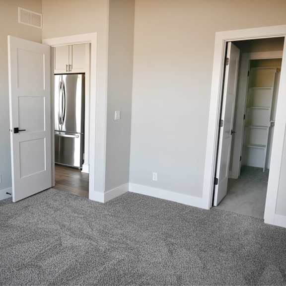 a room with a carpeted floor and a refrigerator in the corner.