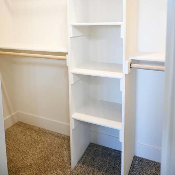 a white shelving unit in a room with carpeted flooring.