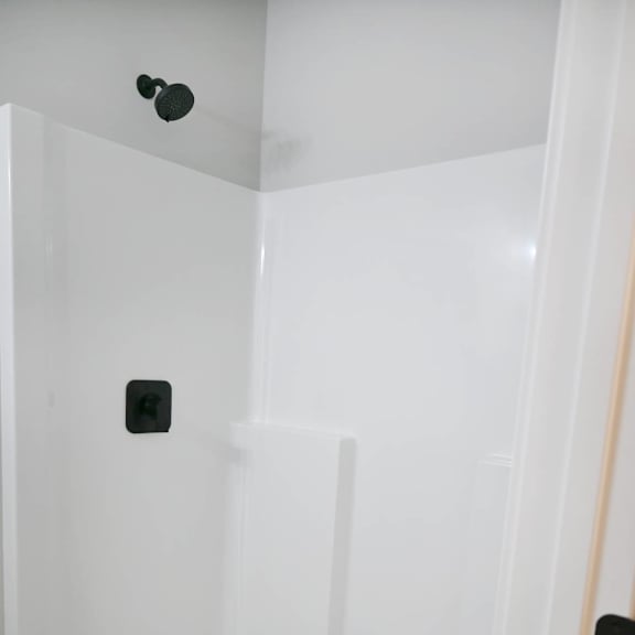 a white shower stall with a drain in the middle.