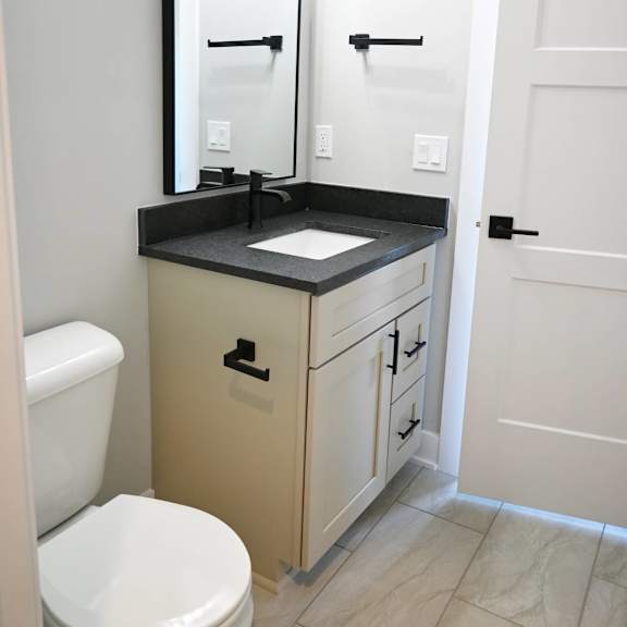 a bathroom with a toilet, sink, and mirror.