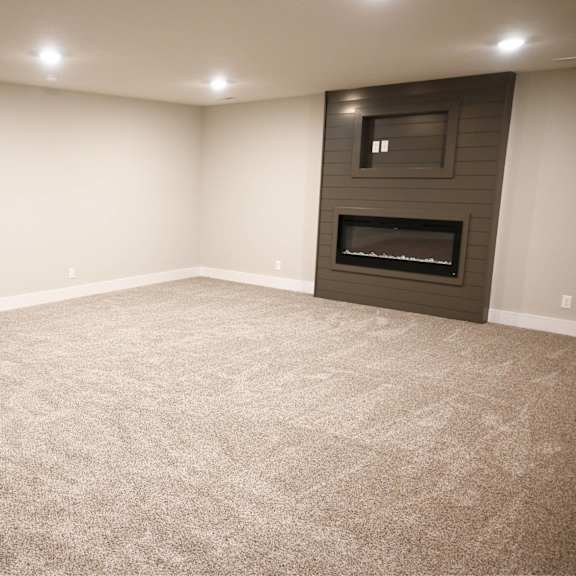 a spacious room with a carpeted floor and a fireplace.