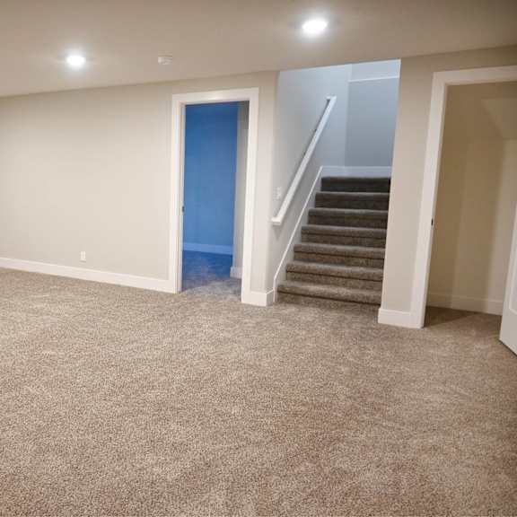 a room with a carpeted floor and a staircase leading to another room.