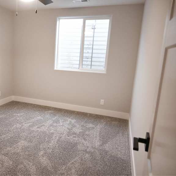 a room with a grey carpet and a window with blinds.