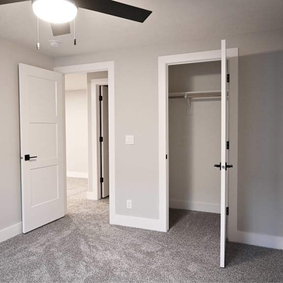 a room with a ceiling fan and two doors.