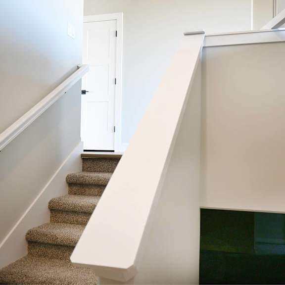 a staircase with a carpeted runner and white handrail.
