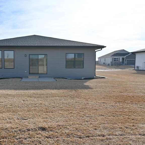 a grey house with a brown lawn in front of it.