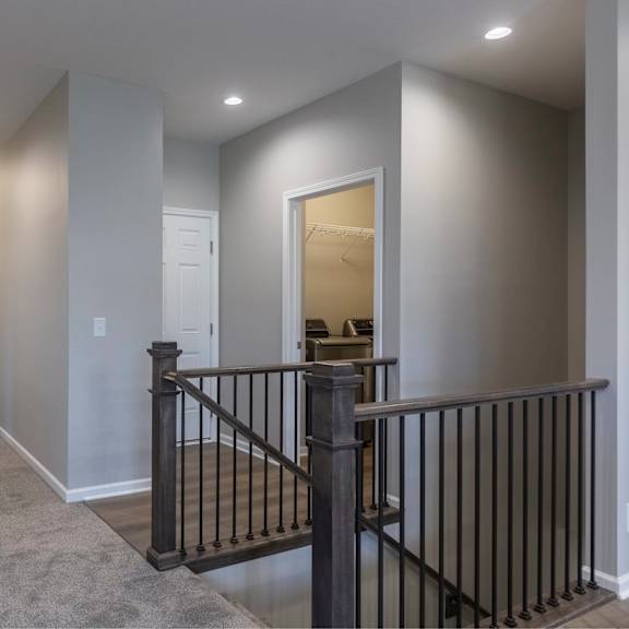 a hallway with a black railing and a white door.