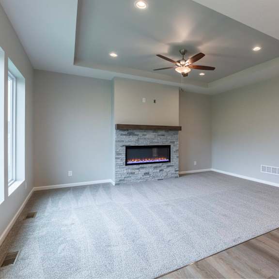 a spacious living room with a fireplace and a ceiling fan.
