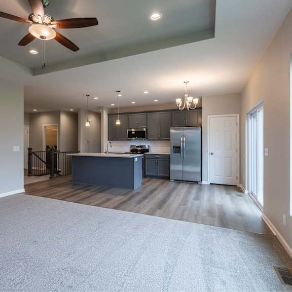 a spacious kitchen and living room with a ceiling fan and hardwood floors.
