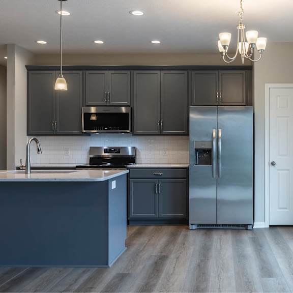 a kitchen with a refrigerator, sink, and cabinets.