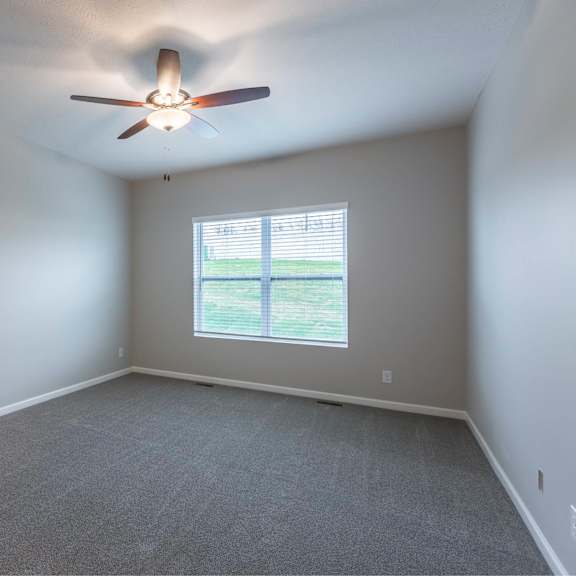 a room with a ceiling fan and a window.
