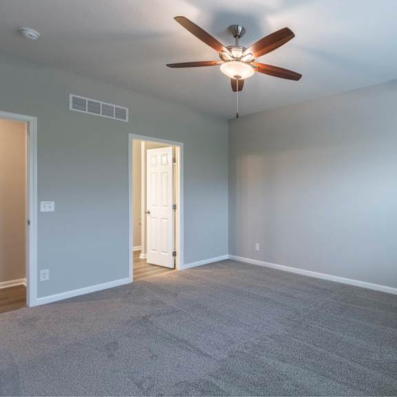 a room with a ceiling fan and carpeted floor.