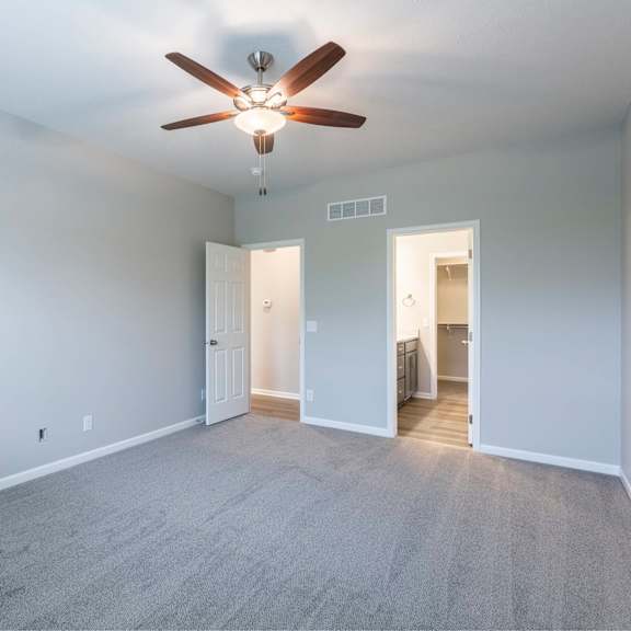 a room with a ceiling fan and carpeted floor.