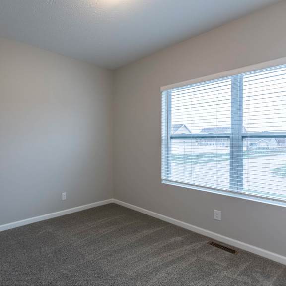 a room with a carpeted floor and a window with blinds.