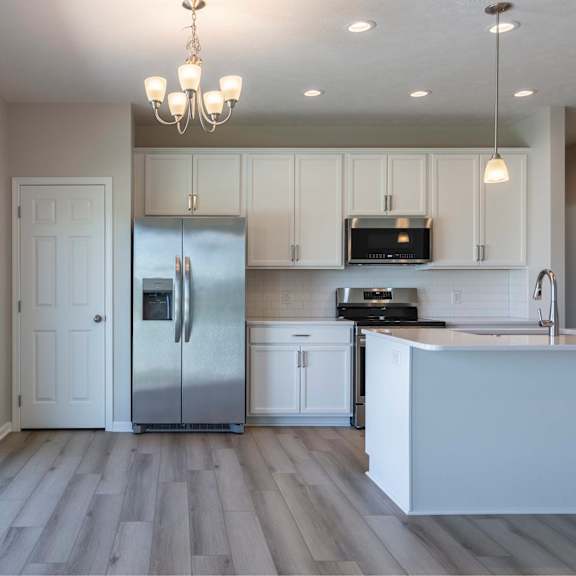 a kitchen with a refrigerator, microwave, and oven.