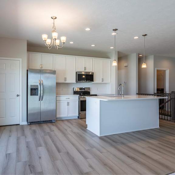 a modern kitchen with a refrigerator, microwave, and oven.