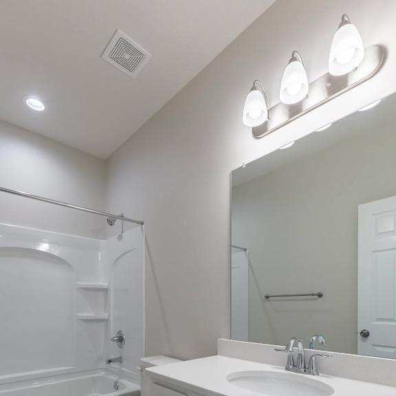 a white bathroom with a toilet, sink, and mirror.