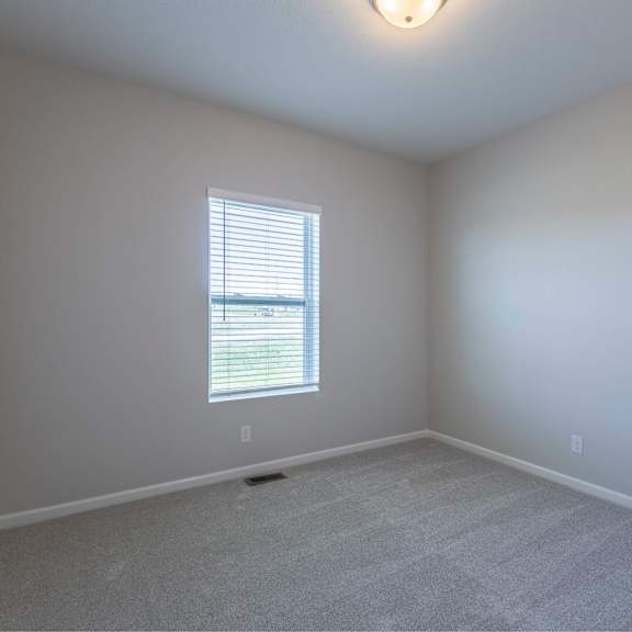 a room with a carpeted floor and a window with blinds.