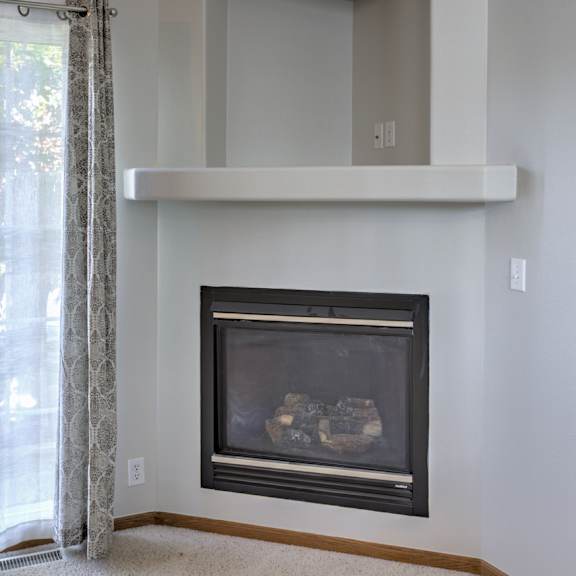 a fireplace with a white mantle and a black fireplace screen.