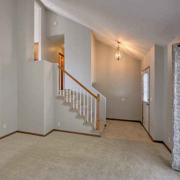 a spacious living room with a staircase leading to the upper level.
