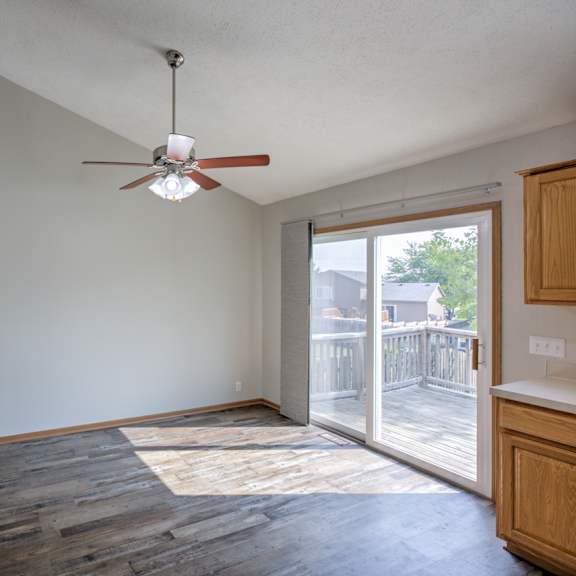 a room with a ceiling fan and sliding glass doors.