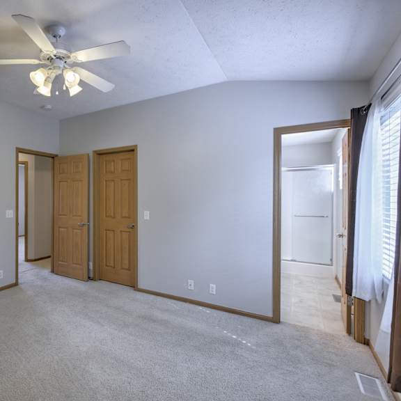 a room with a ceiling fan and carpeted floor.
