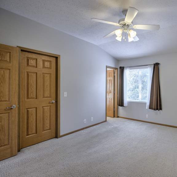 a room with a ceiling fan and a window with curtains.