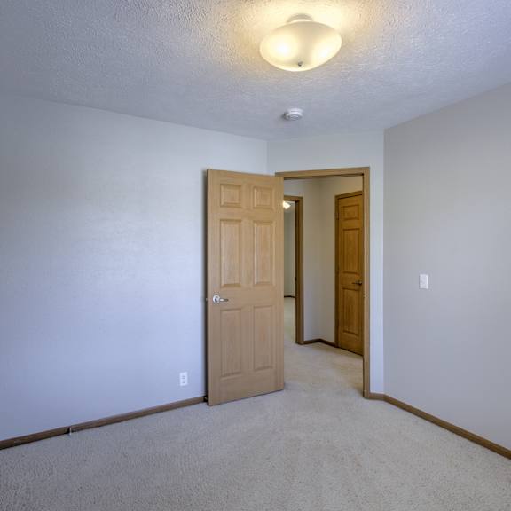 a room with a carpeted floor and two wooden doors.