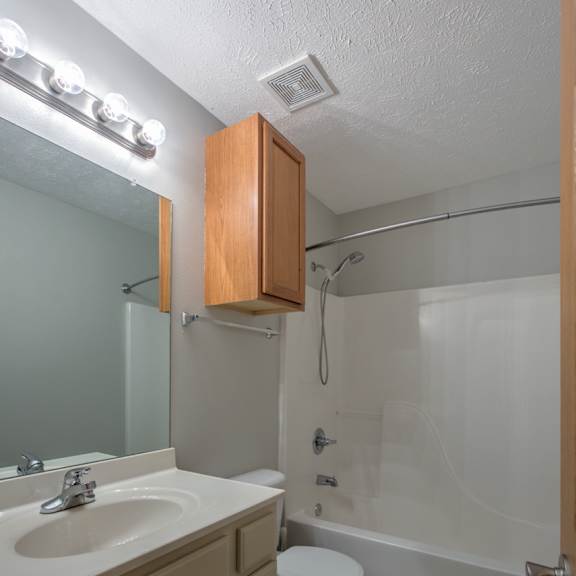 a bathroom with a toilet, sink, and shower.