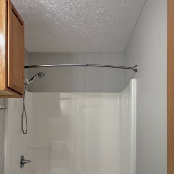a small bathroom with a toilet, a shower with a glass door, and a wooden cabinet.