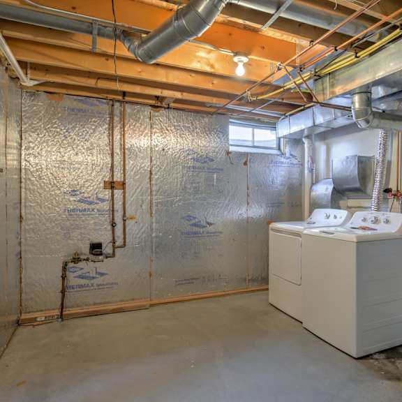 a room with a wall covered in insulation and pipes running along it.