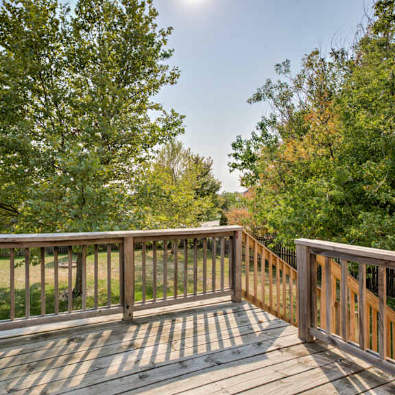 a wooden deck with a railing and trees in the background.