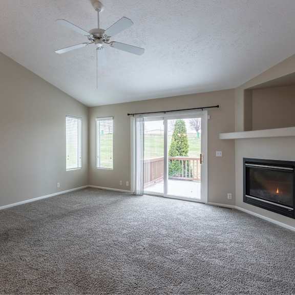 a spacious living room with a fireplace and sliding glass doors.