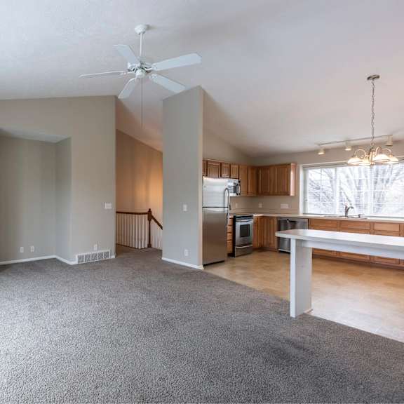 a spacious living room with a fireplace and a ceiling fan.