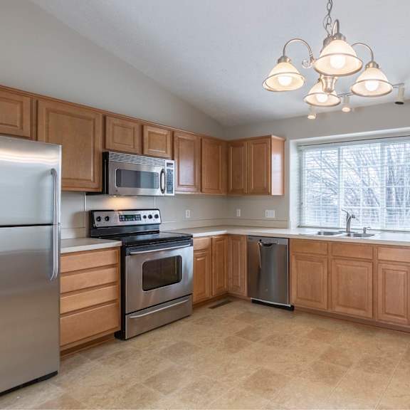 a kitchen with wooden cabinets and a stainless steel refrigerator.