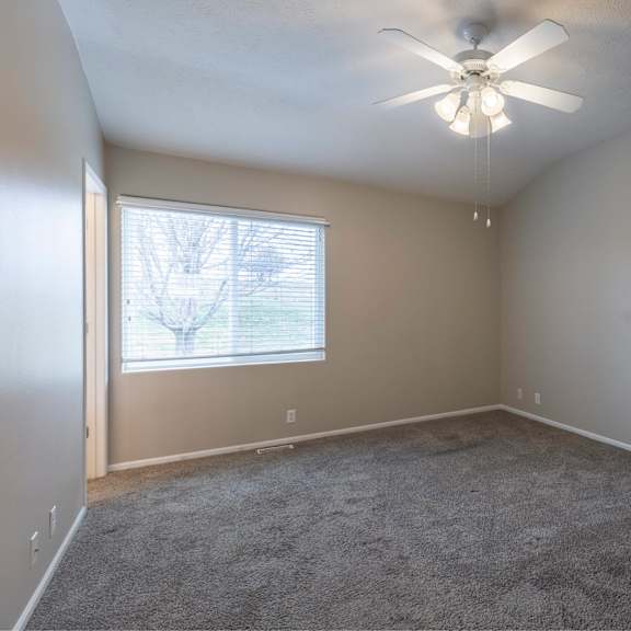 a room with a ceiling fan and carpeted floor.