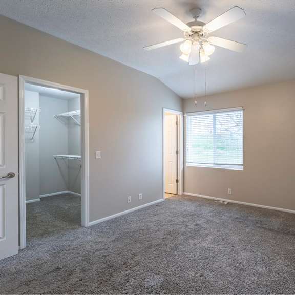 a room with a ceiling fan and a door leading to a bathroom.