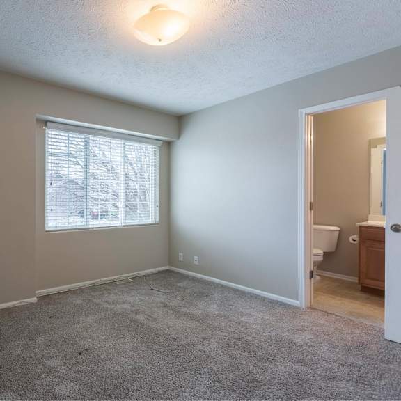 a room with a carpeted floor and a window with blinds.