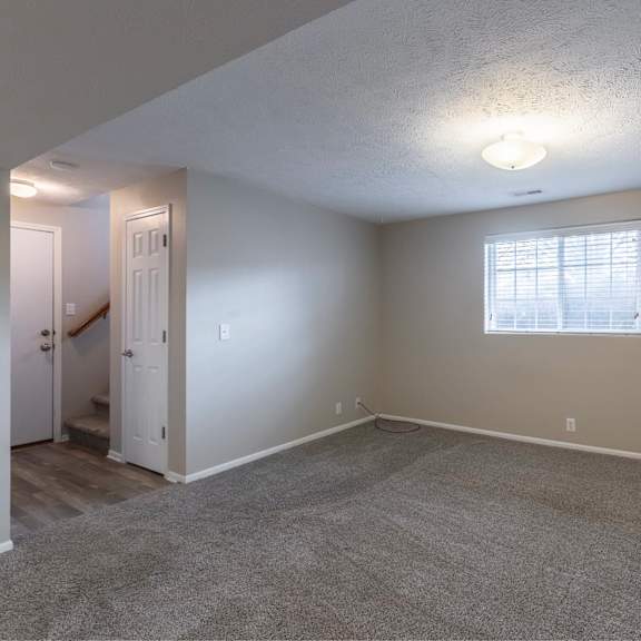 a room with a carpeted floor and a window with blinds.