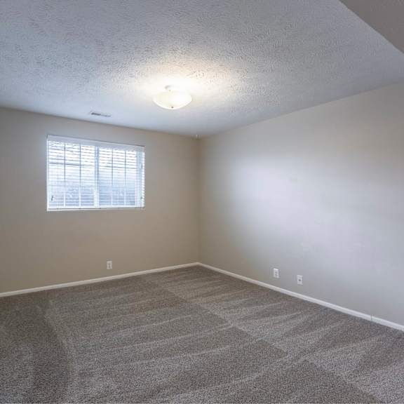 a room with a carpeted floor and a window with blinds.
