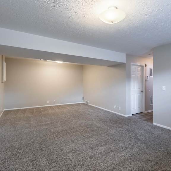 a spacious room with a carpeted floor and white walls.
