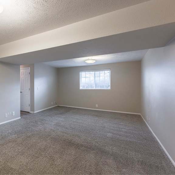 a room with a carpeted floor and a window with blinds.