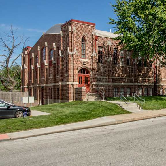 a red brick building with a green tree in front.