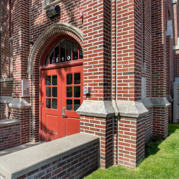 a red door is on the side of a brick building.