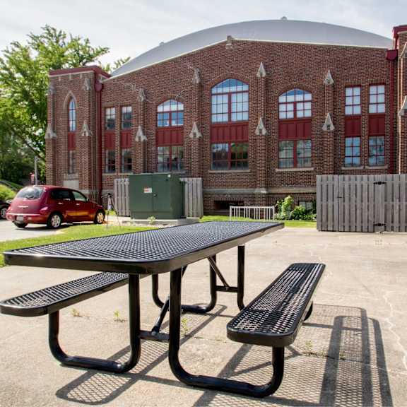 a picnic table is in front of a brick building.
