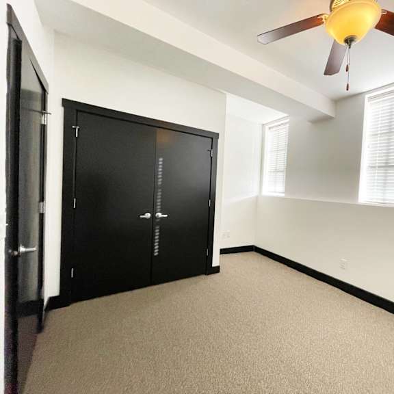 a room with a ceiling fan and a black wardrobe.